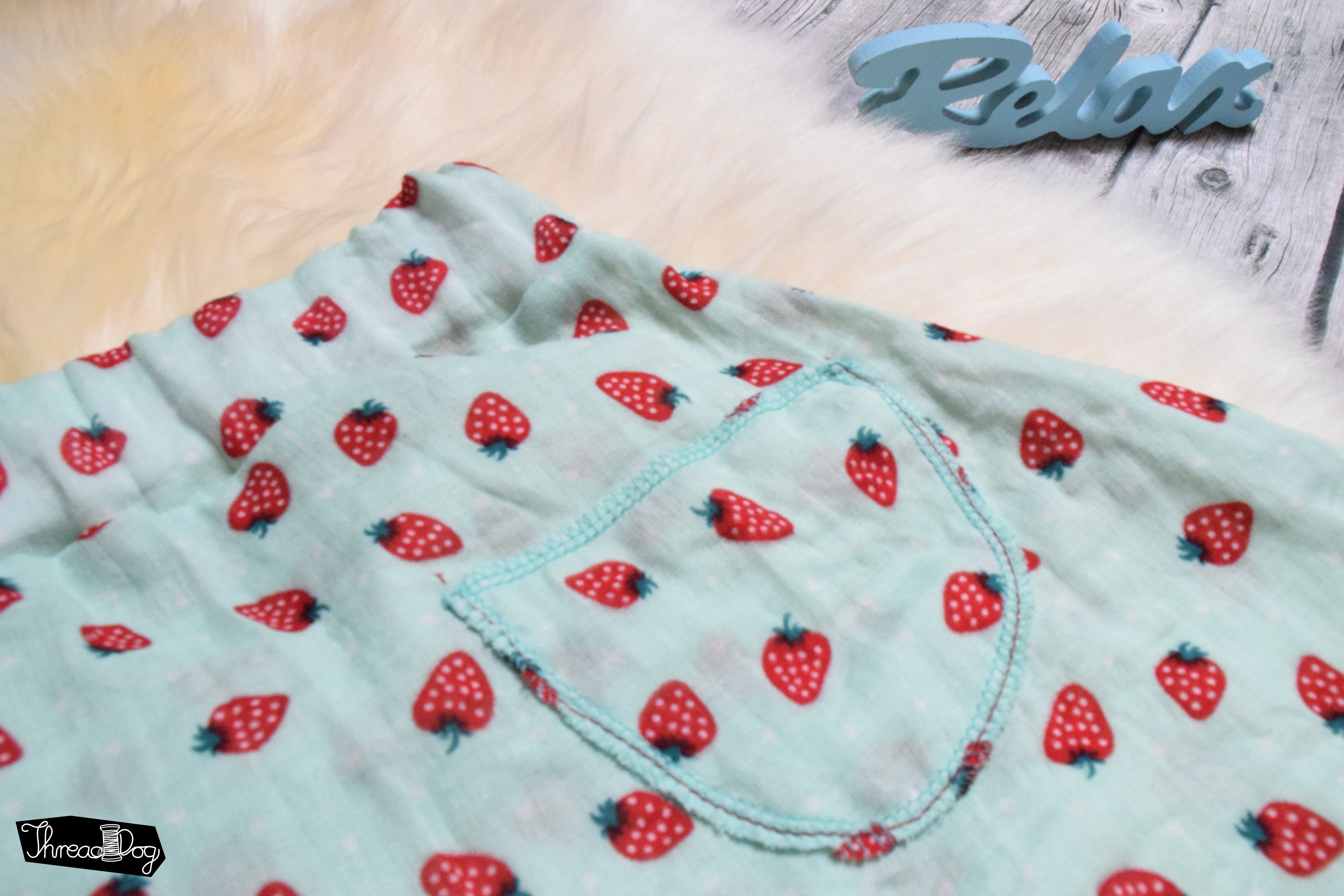 grüne Musselin-Hose mit Erdbeeren. Detailansicht einer Gesäßtasche.